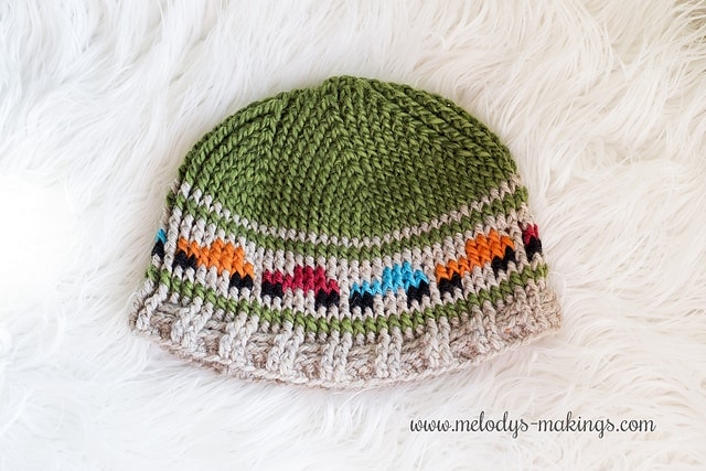 Crochet  graph beanie in green with cream/tan stripe with different color trucks on stripe.