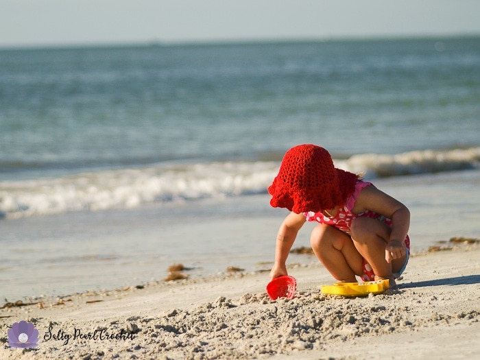 My daughter wearing her Scalloped Toddler Beach Hat while playing in the sand.
