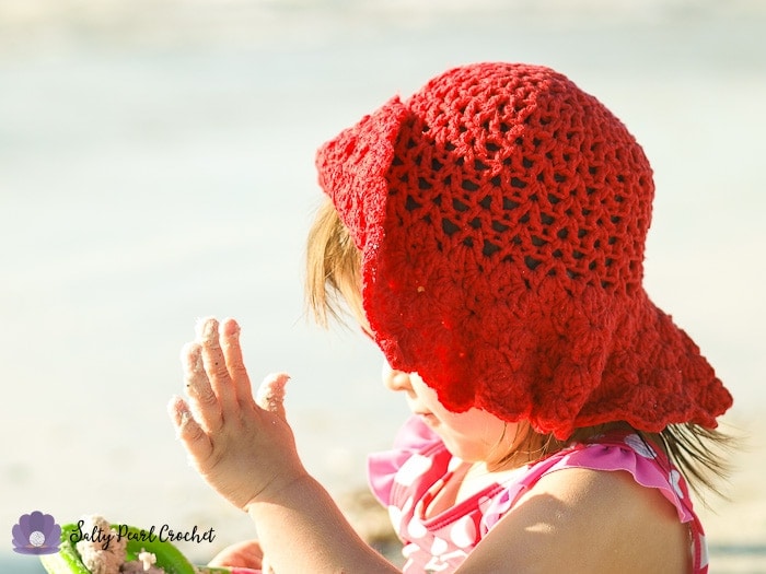 My daughter plays in the sand while wearing her Scalloped Toddler Beach Hat