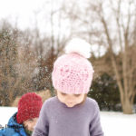 Girl wearing a pink crochet hat in the snow