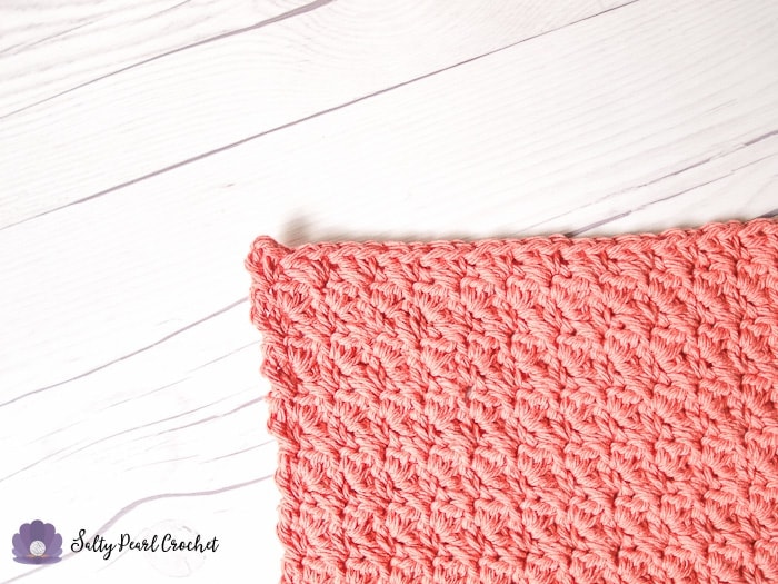 a coral pink washcloth on a white wood surface