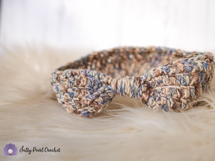 An easy to crochet ear warmer pattern sample on a furry sheepskin rug.