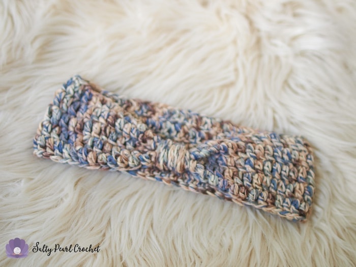 An easy crochet ear warmer laid on a sheepskin rug.