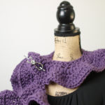 Tight shot showing the ruffle scarf wrapped around the neck of a bust form.