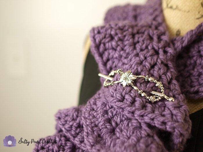 Closeup of the shawl pin securing the chunky crochet ruffle scarf.