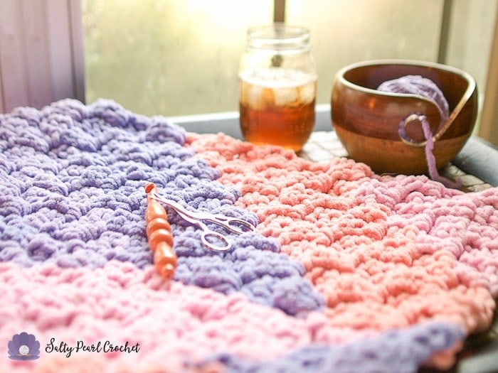 Close up of pink and purple crochet blanket showing the detail of the crochet stitches. 