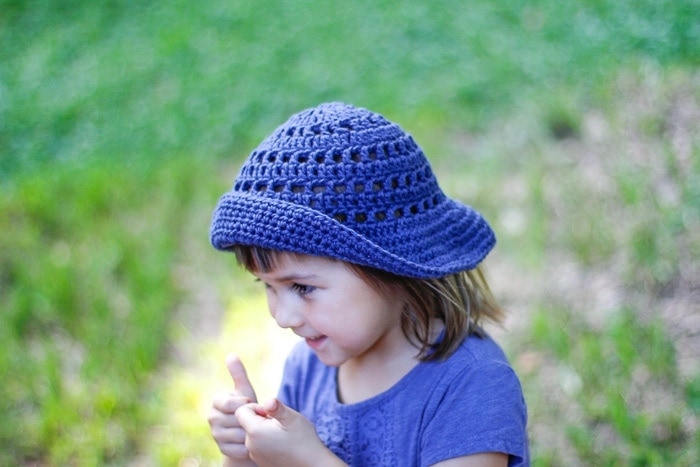 Little girl wearing a blue crocheted sun hat with a floppy brim