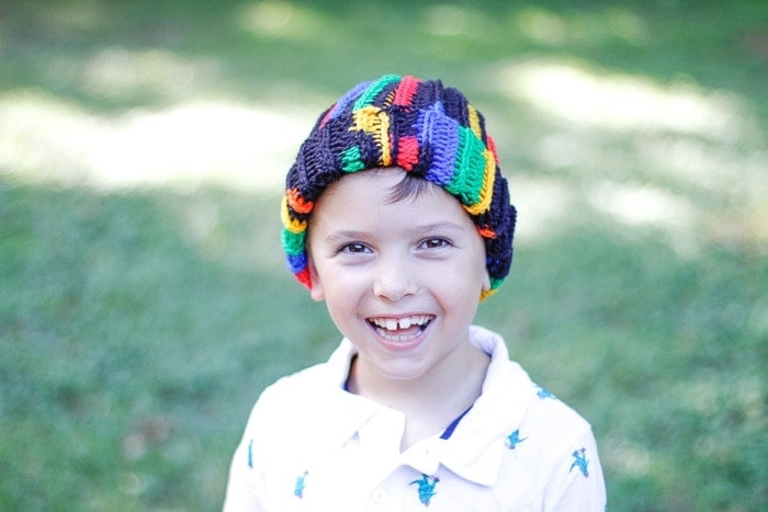 Little boy smiling and wearing a multi-color ribbed crochet beanie