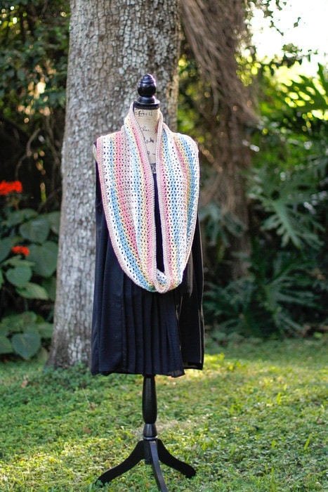 Crochet scarf on a dressform in front of a tree.