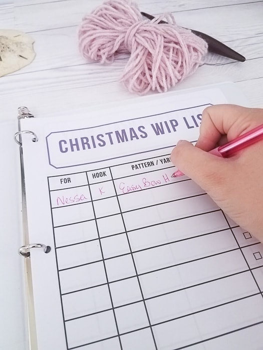 Hand writing on a Christmas WIP List page to organize crochet christmas gift projects.
