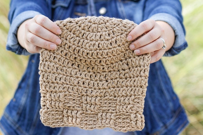 Woman holding a sample of the crochet basketweave beanie pattern.