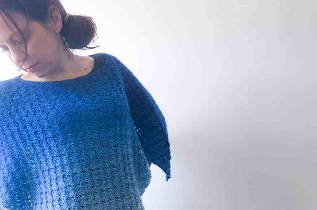 Woman wearing a blue crochet poncho. 