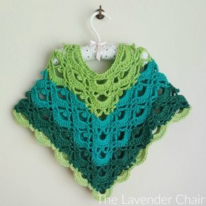 A a light green, dark green and teal crochet poncho displayed on a satin hanger. 