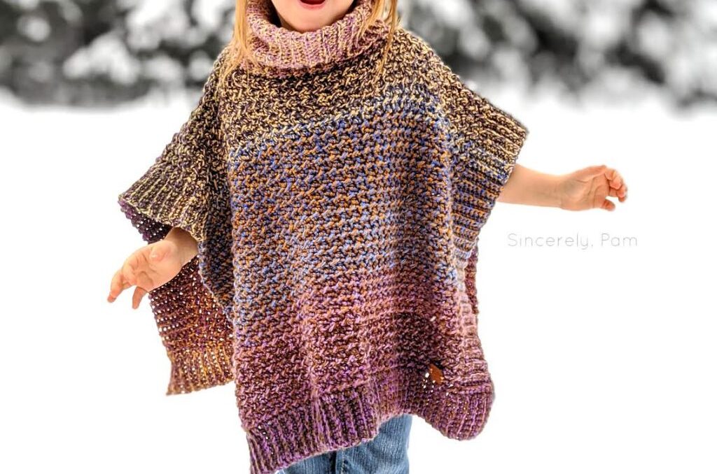 A young girl outside in the snow wearing a colorful, highly textured crochet poncho. 