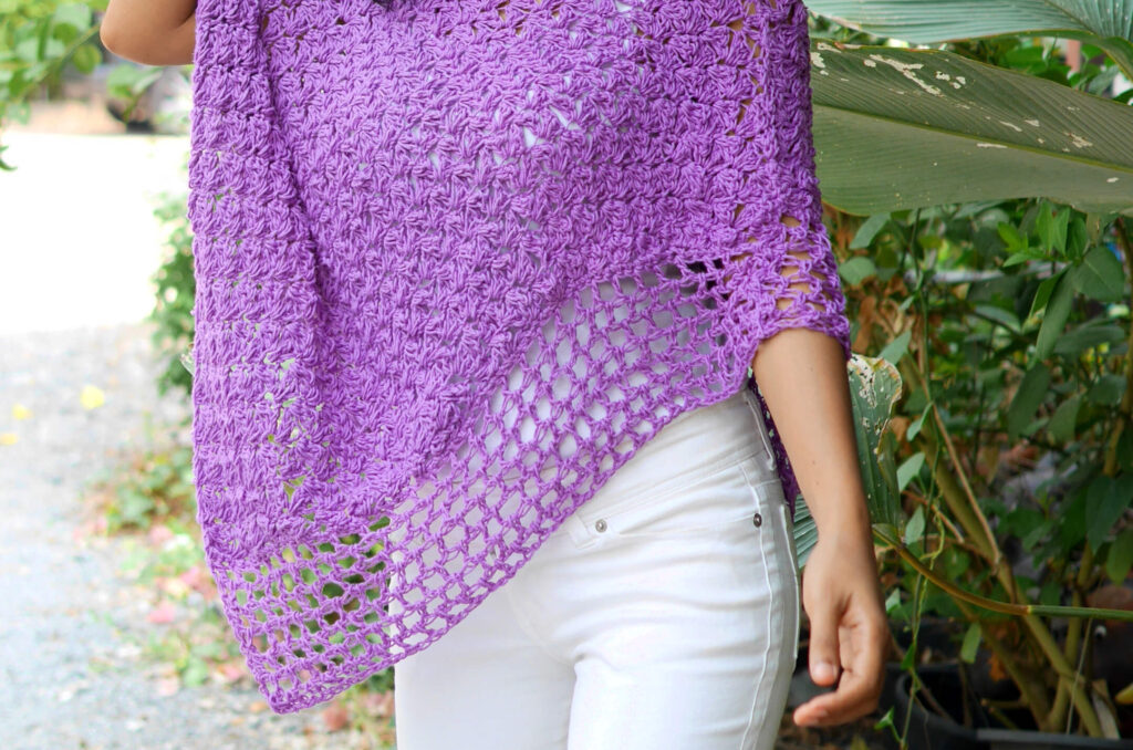 Woman wearing a purple crochet poncho. 