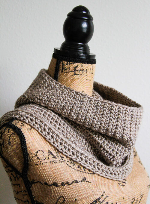 Crochet taupe cowl on a mannequin. 