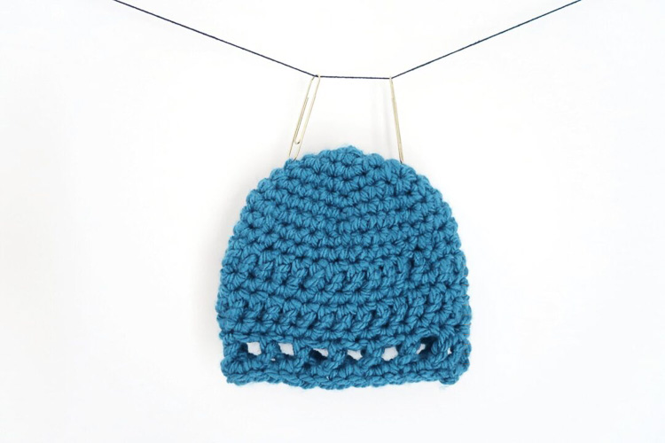 A blue crochet baby hat made with chunky yarn.