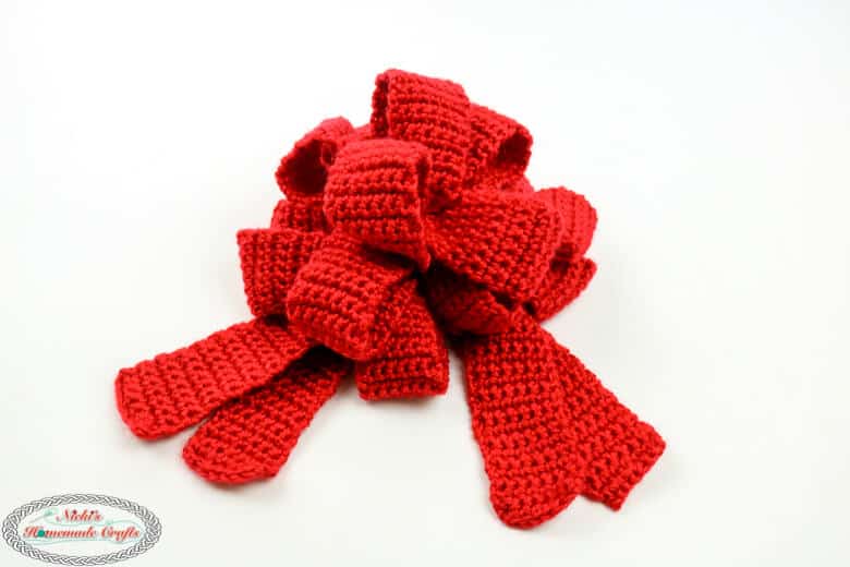 A red holiday crochet bow on a white background
