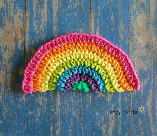 a crochet rainbow dishcloth on a blue table