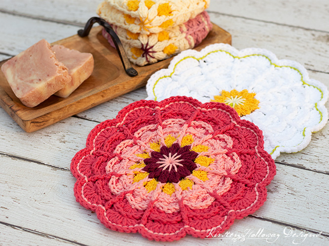 two pretty crochet flower dishcloths on a table with a tray of soap