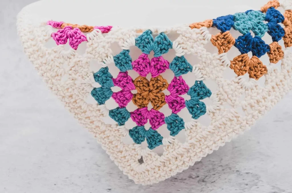 a crochet dishcloth made of 4 granny squares on a white bowl