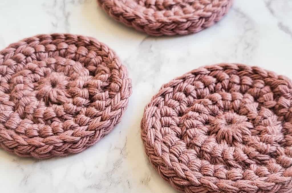 a set of round crochet scrubbies for makeup removers on a white marble surface