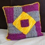 A crocheted pillow that looks like a wheel quilt block