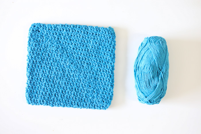 A turquoise double layer crochet potholder with a ball of matching yarn