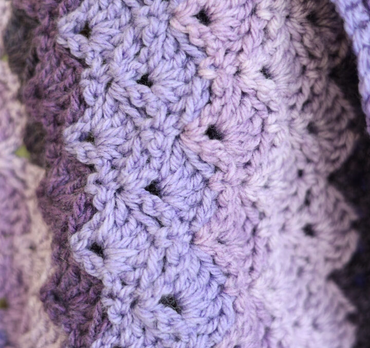 Close up of a purple striped yarn in a crochet lace stitch used in the Mermaid Tears Crochet Wrap Pattern.