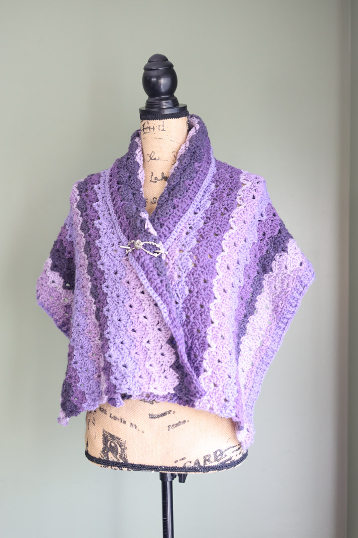 A purple crochet lace shawl wrap on a mannequin.