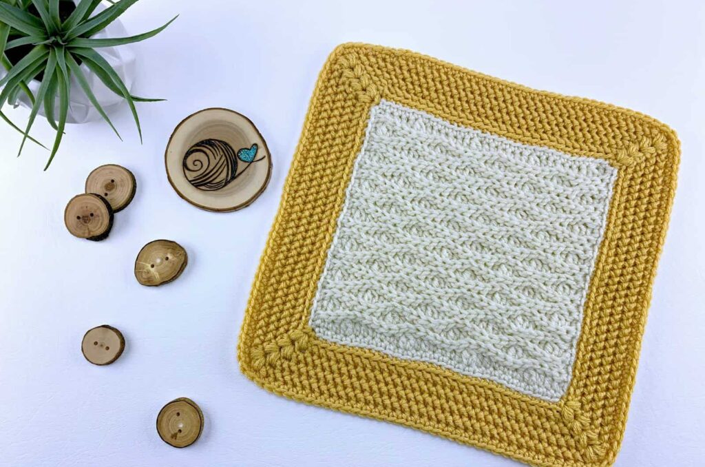 A highly textured cream colored crochet afghan square with a golden yellow border.