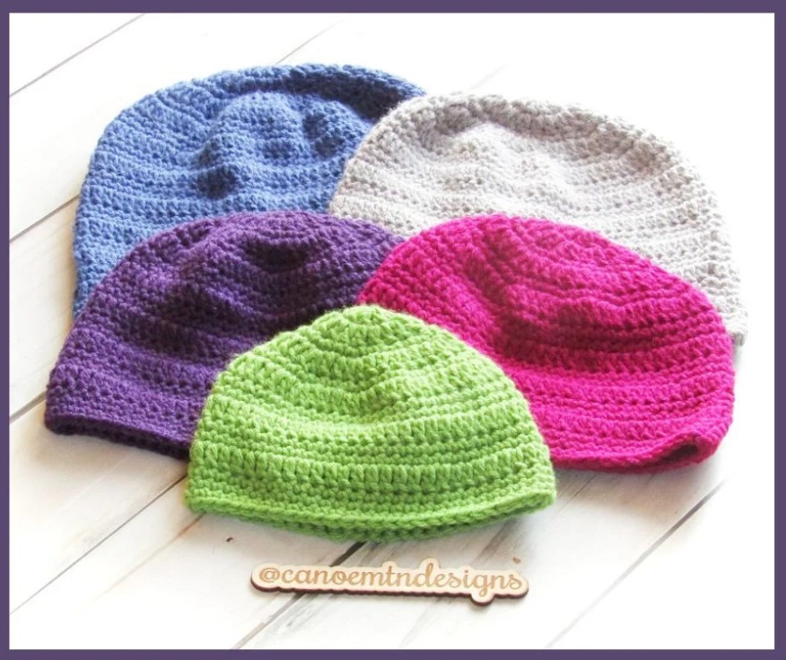 5 brightly colored crochet charity beanies on a table