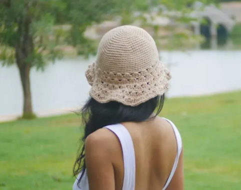 Woman wearing a tan crochet summer hat.