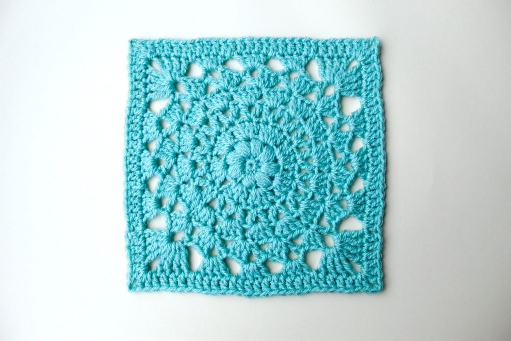 Blue crochet granny square on white background. 