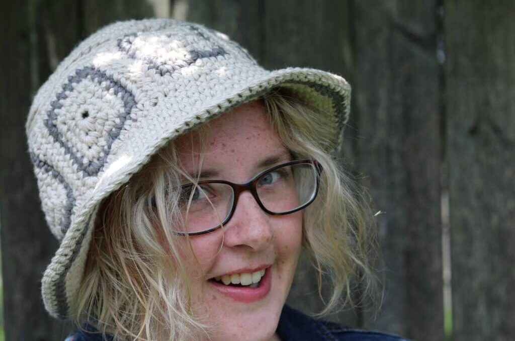 Woman wearing gray crochet bucket hat. 