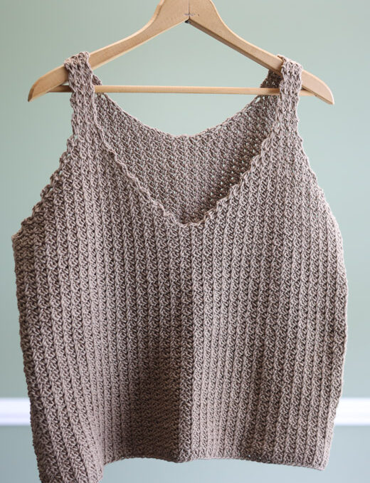 a crochet cami top on a hanger in a green room