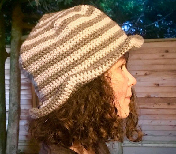 Girl wearing a tan and brown striped crochet bucket hat.