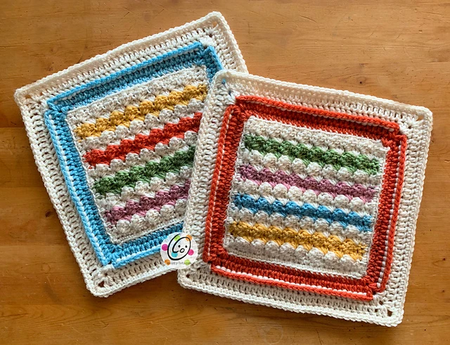 Two colorful striped crocheted afghan squares on table. 