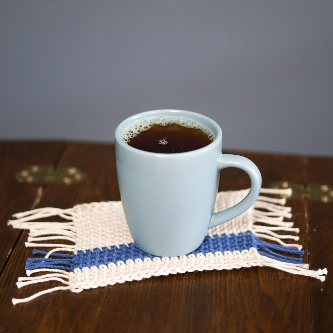 a blue tea mug on a crochet mug rug with a blue stripe