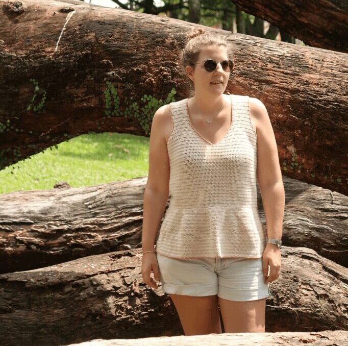 Woman wearing a cream crochet tank top and sunglasses. 
