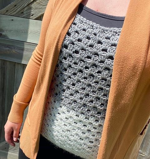 Woman wearing a gray and white crochet granny stripe tank top under a mustard yellow cardigan.