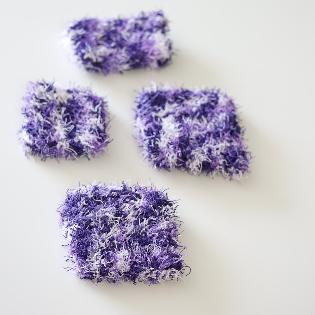 4 purple crochet dish scrubbies on a white table