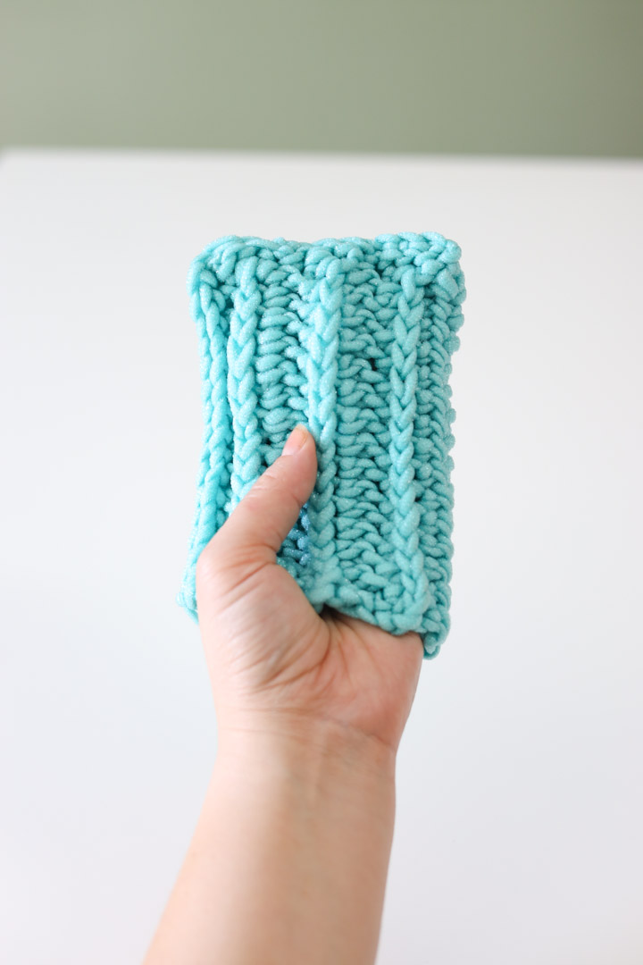 holding up a crochet scrubber mitt made with scrubby yarn