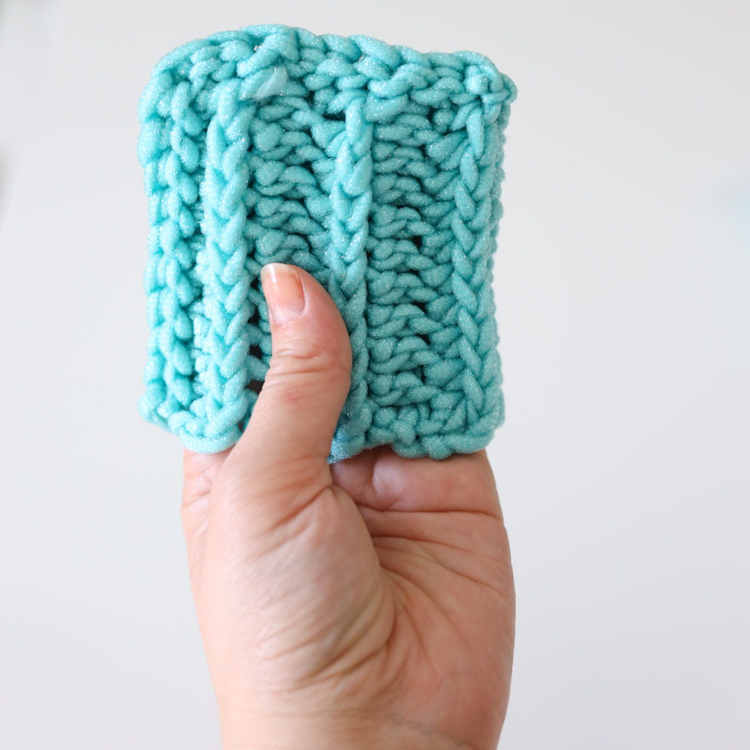 a small teal scrubby mitt held by hand