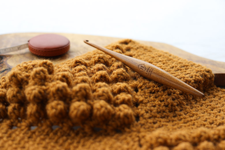 a crochet hook on a bobble stitch blanket square