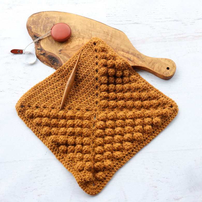 a furls crochet hook on a crochet blanket square pattern using the crochet bobble stitch