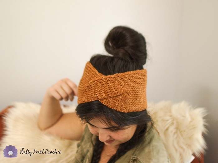 Woman with her hair in messy bun wearing a burnt orange crochet headband.
