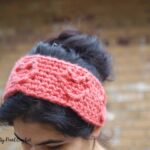 Woman outside wearing a crocheted coral headband with raised heart detail.